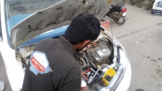 Mechanic working in the engine bay of a car at the workshop