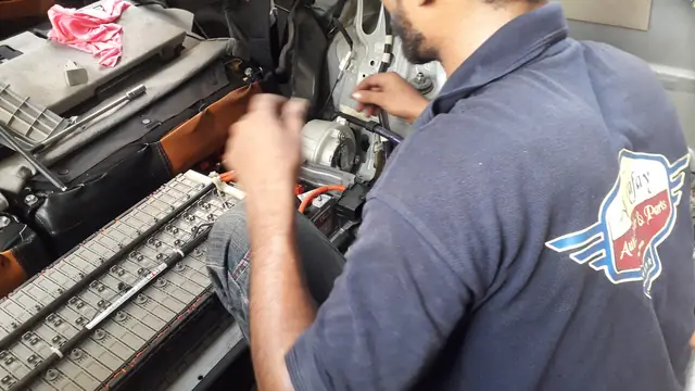 Al-Rafay mechanic in a workshop shirt with the winged Al-Rafay badge, leaning into an engine bay