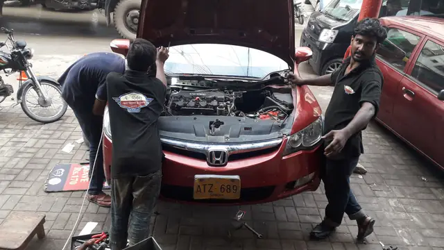 Mechanics working on a Honda Civic and a Prius inside the Al-Rafay workshop